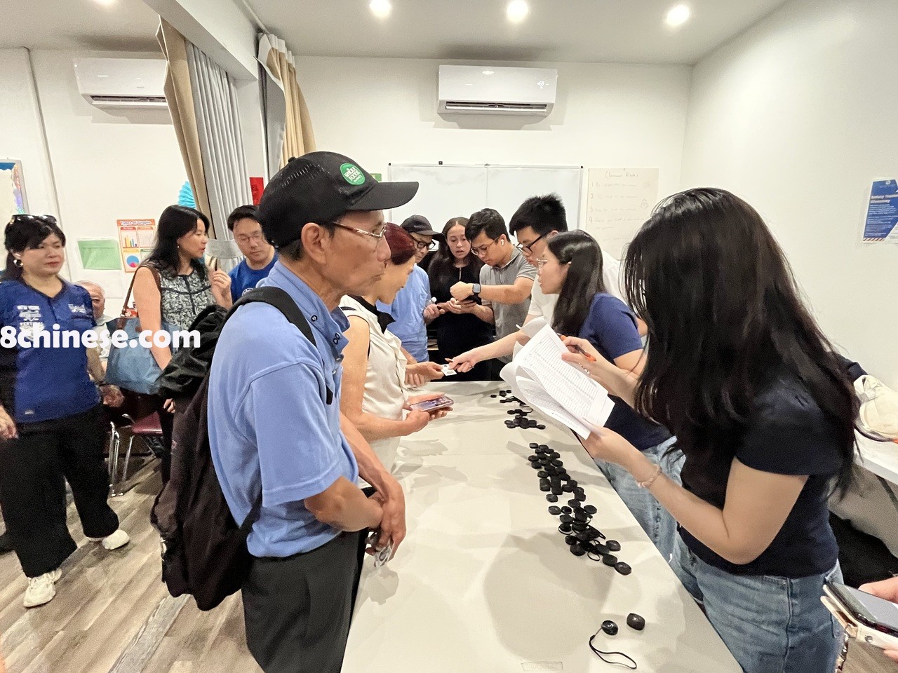 华裔长者到华联会领取安全追踪器，义工正提供帮助。(记者胡声桥╱摄影)